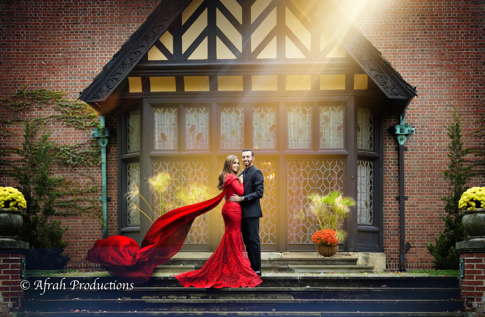 Couple at a Tudor-style estate, bride in a red gown with a flowing train