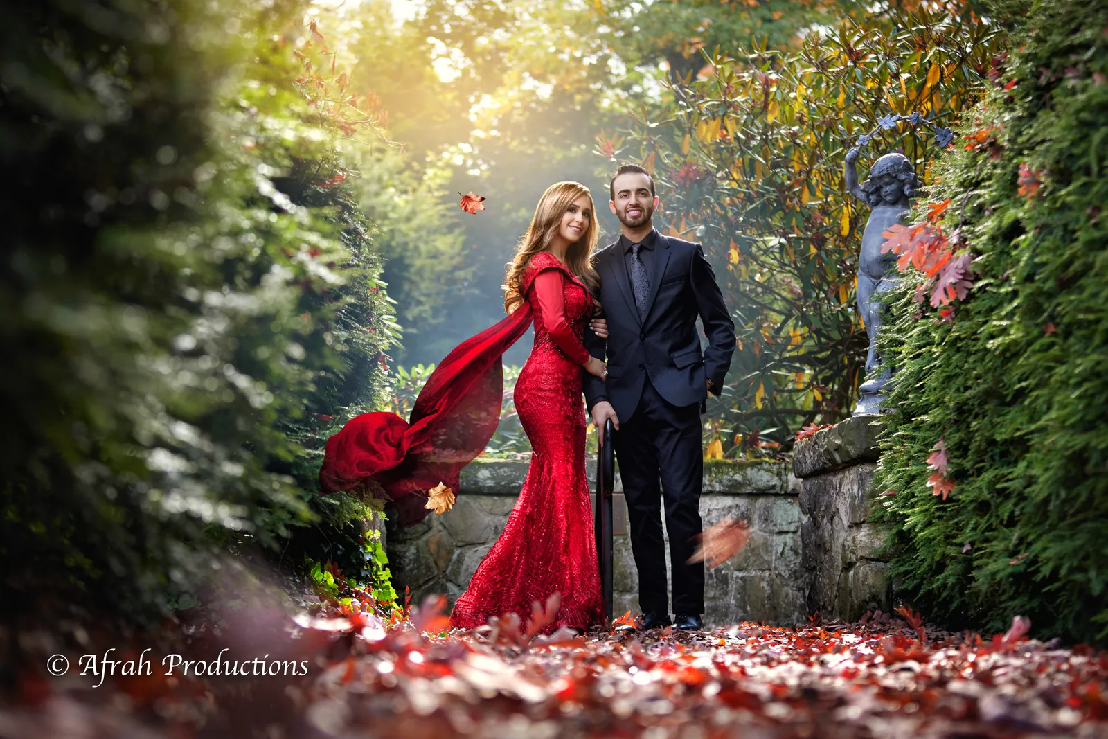 Couple in an autumn garden, bride in a red gown among falling leaves