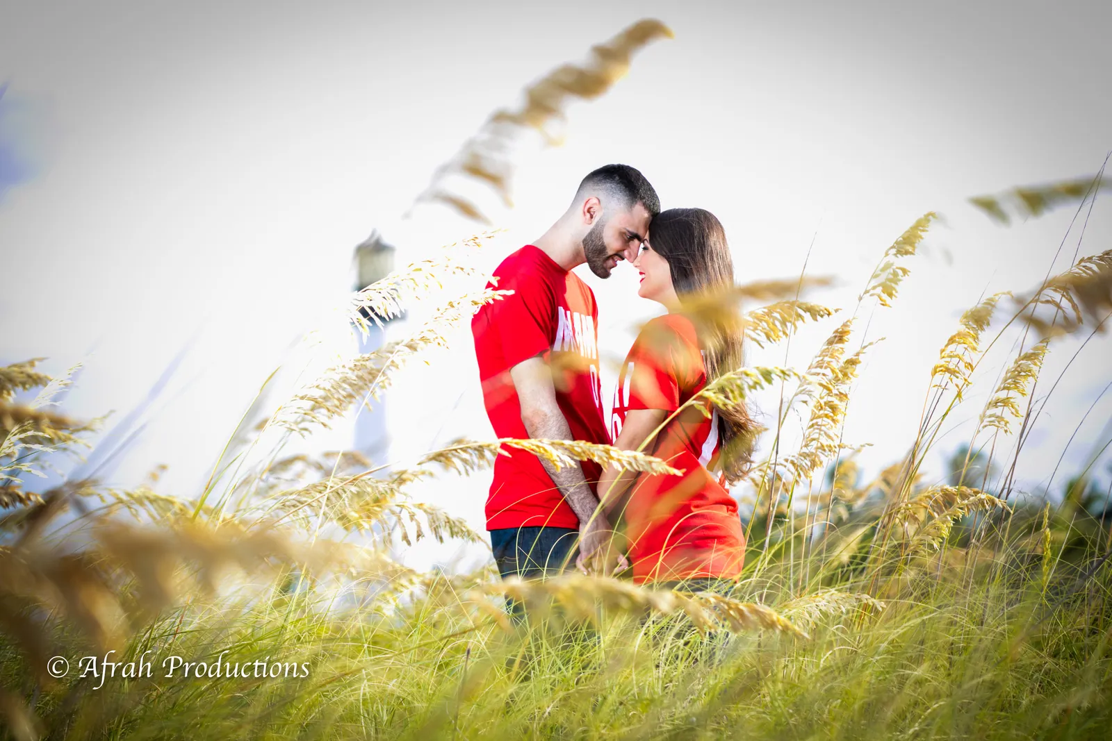 Couple among the sea oats at the beach, bride in a red dress