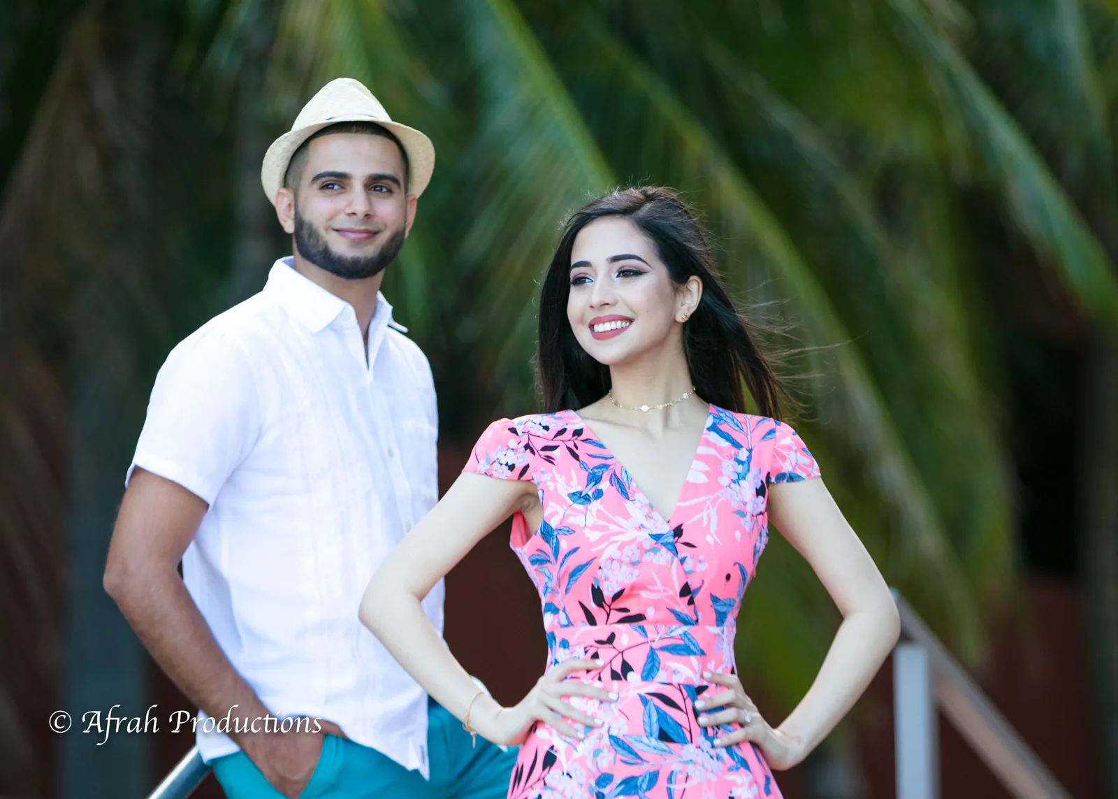 Couple under the palms, her in a bright floral dress